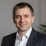 Портрет уверенного российского бизнесмена с дружелюбным взглядом на нейтральном размытом фоне в студии