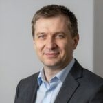 Портрет уверенного российского бизнесмена с дружелюбным взглядом на нейтральном размытом фоне в студии